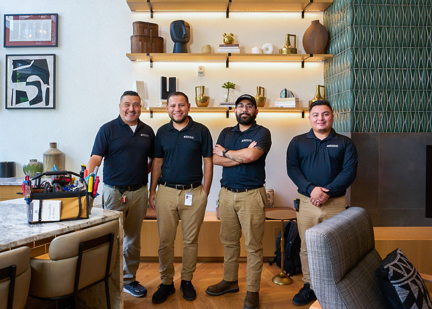 Four individuals in matching shirts pose in a modern interior space.