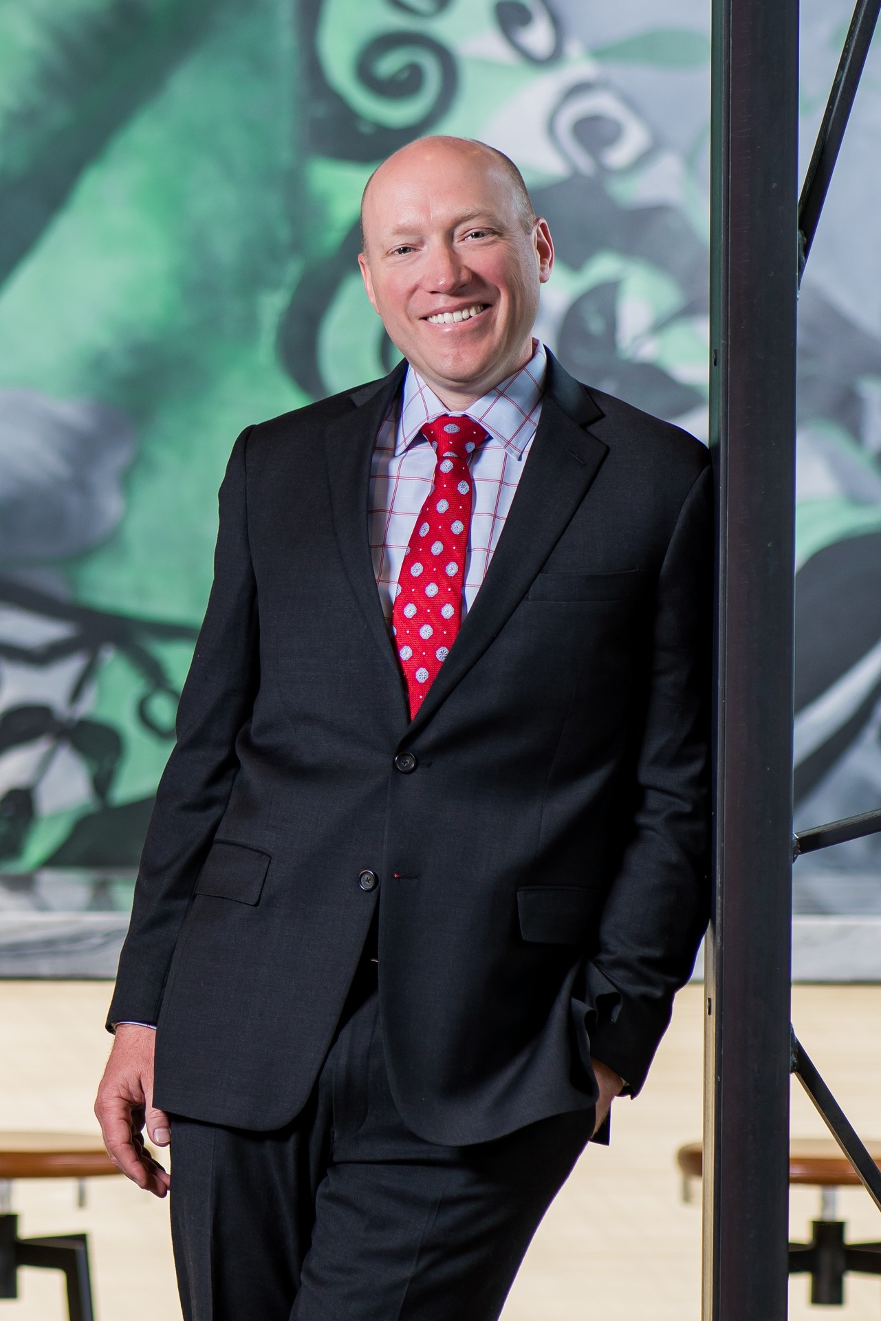 A smiling professional man in a suit stands next to a pillar, associated with Bozzuto Partner.