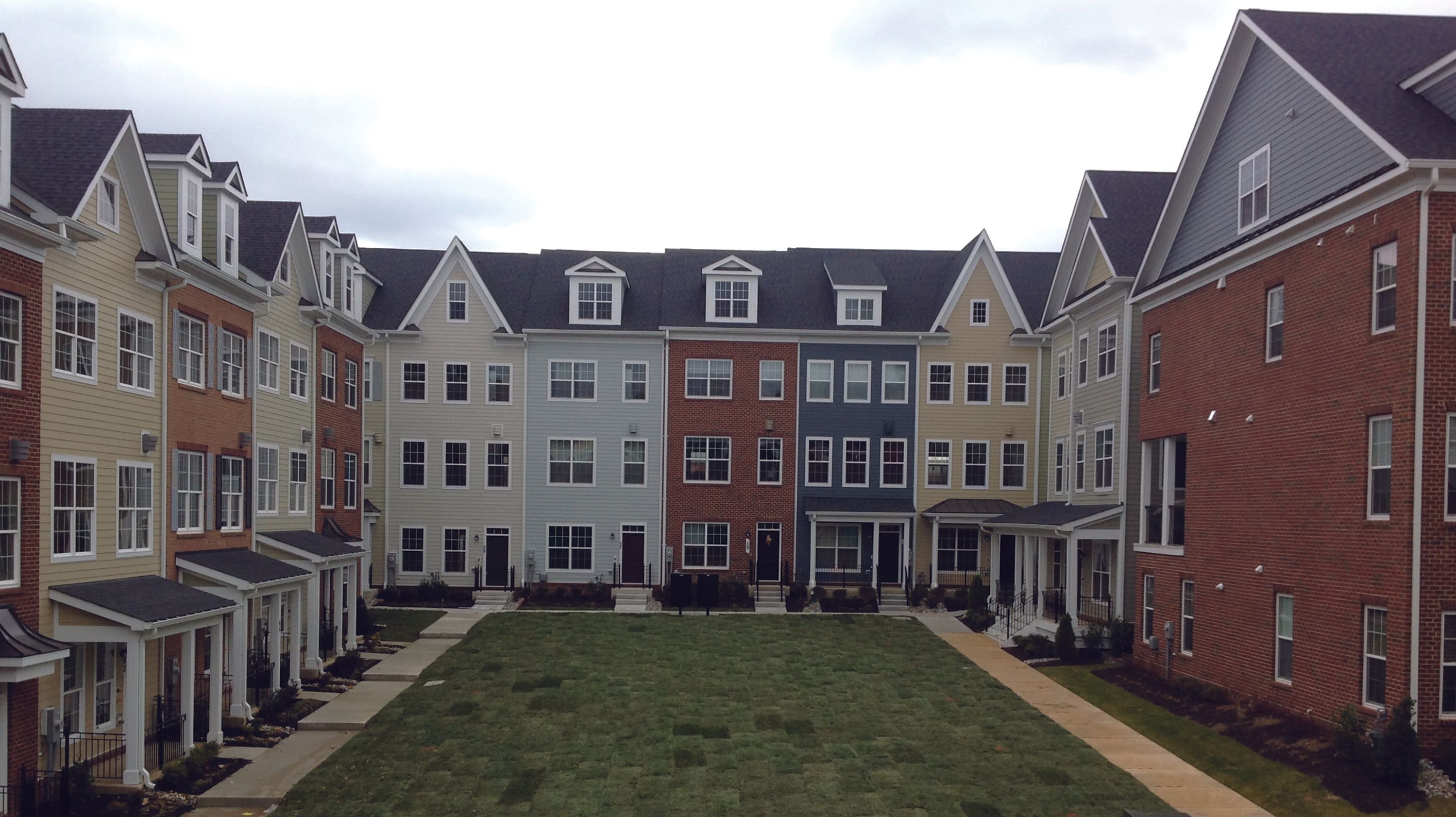 A courtyard flanked by colorful residential buildings under a cloudy sky.