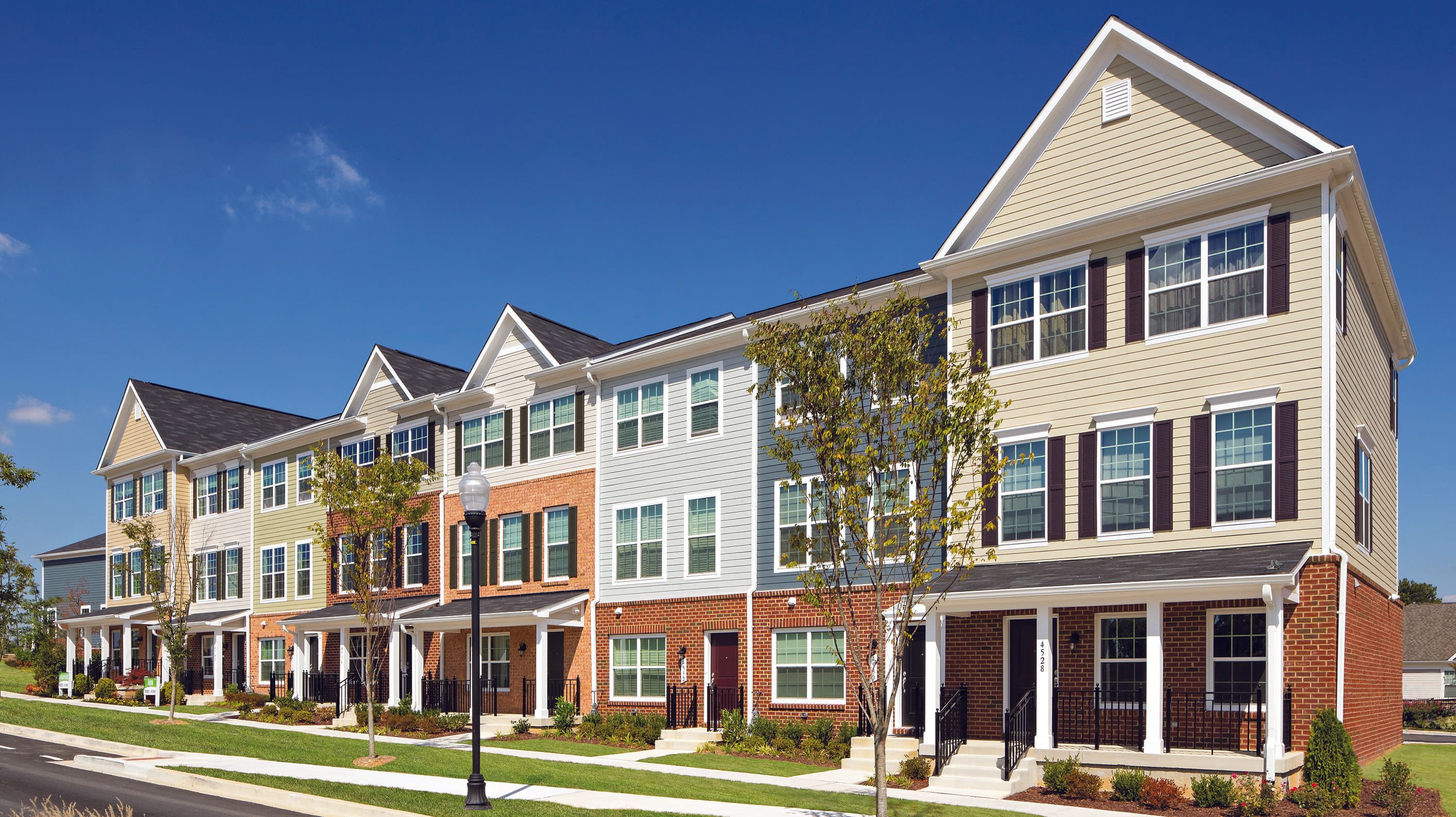 Row of colorful, modern townhouses under a clear blue sky.