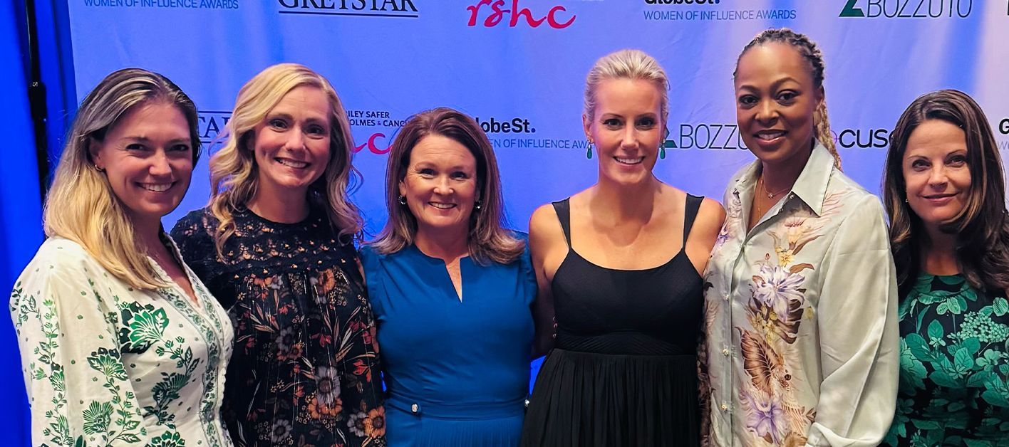 Group of six women smiling together at an event.