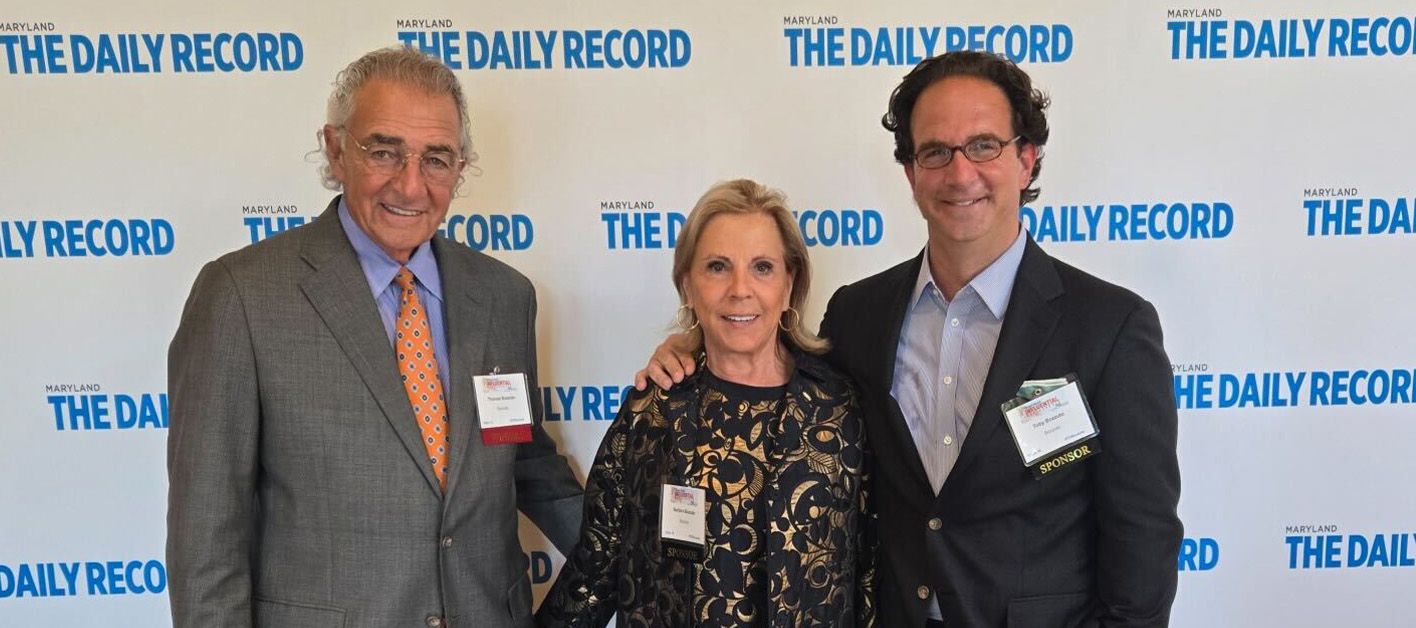 Three people posing in front of a backdrop with "The Daily Record" logo.
