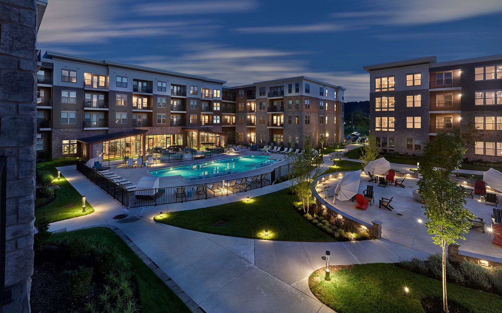 Luxury hotel with a pool and outdoor seating, lit up at dusk.