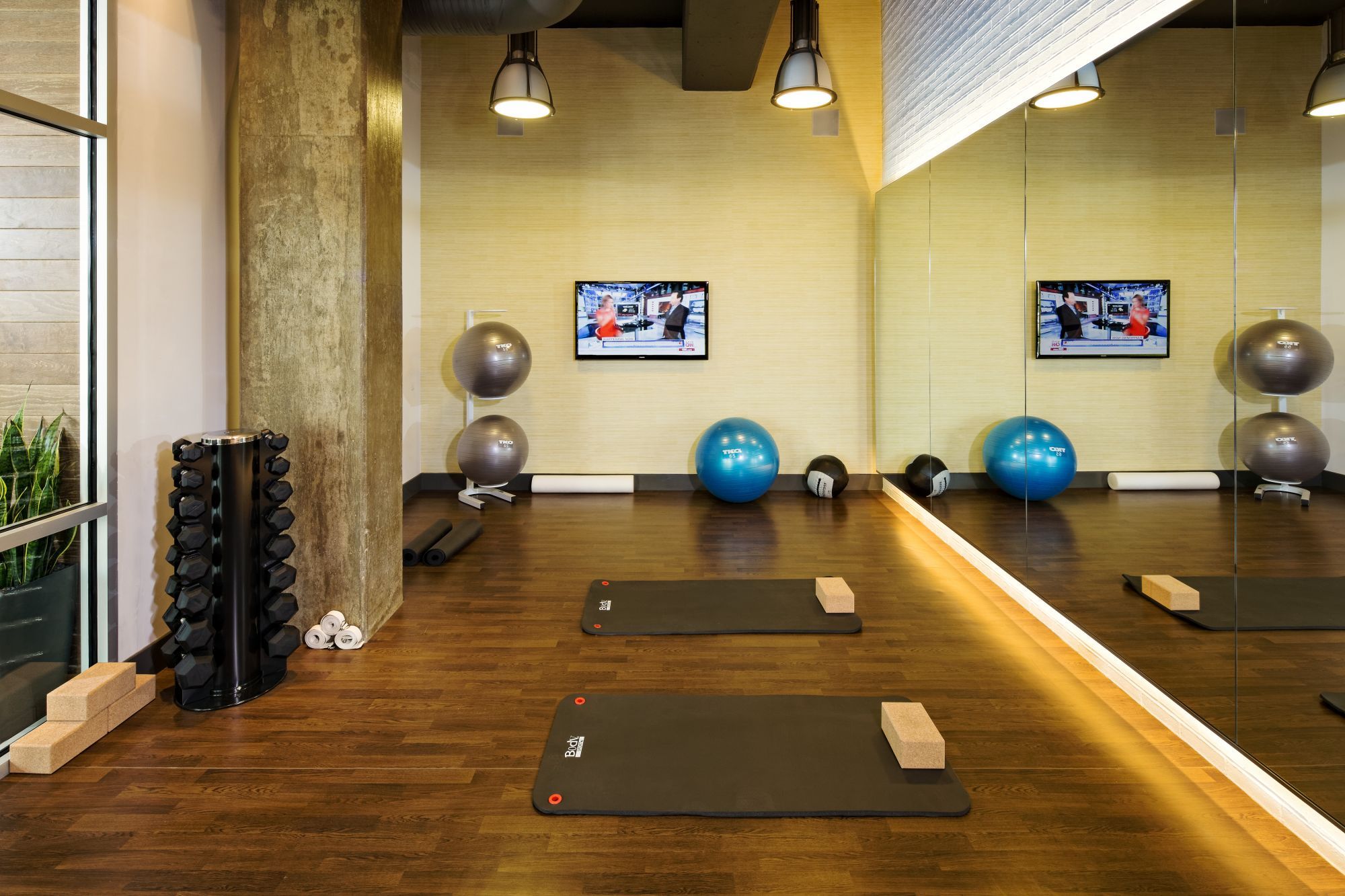 Modern fitness studio with exercise mats, weights, stability balls, and a mirror.