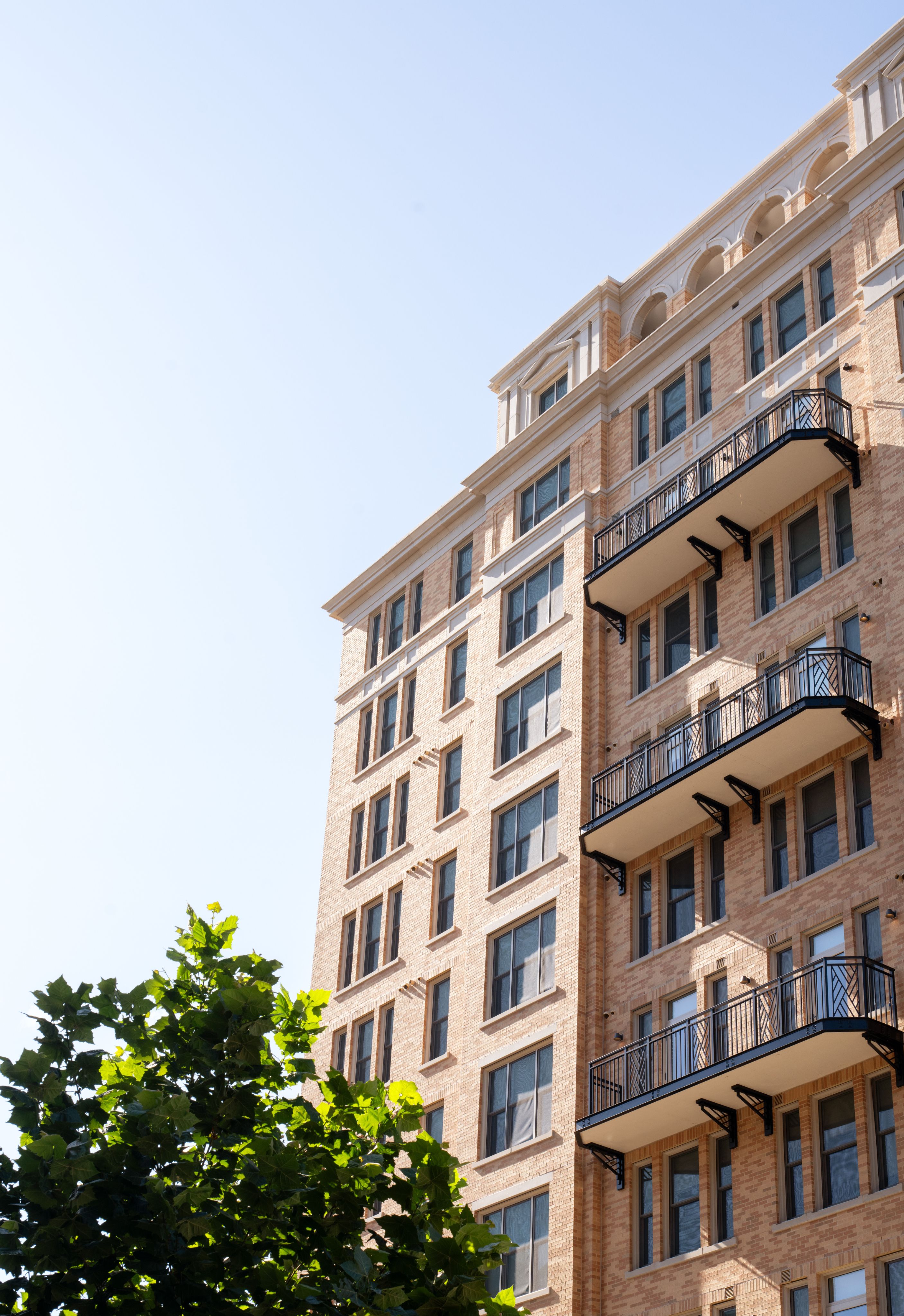 Modern brick apartment building with balconies against a clear blue sky.