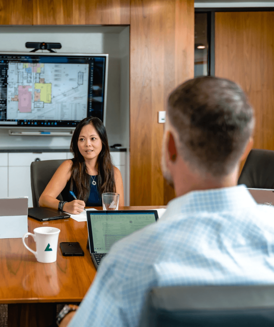 A woman presents during a meeting in a modern conference room.