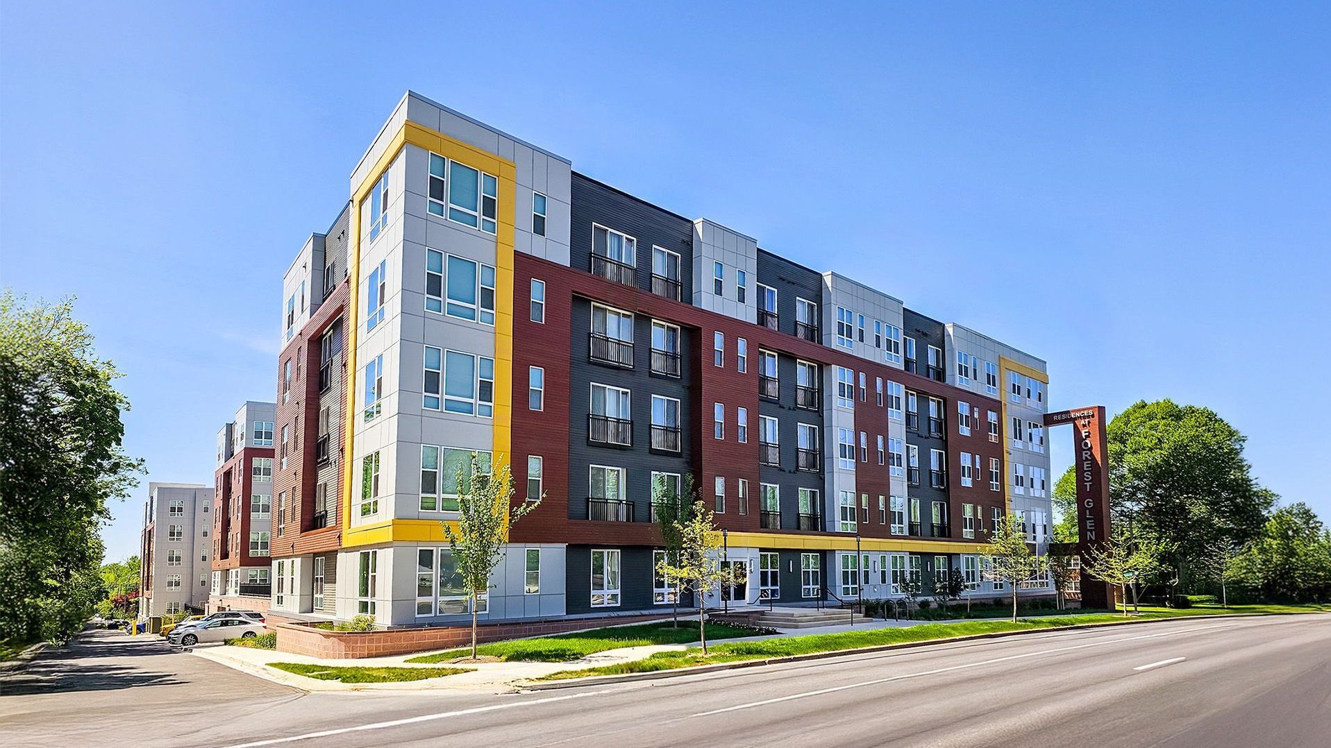 Modern multi-story apartment building with colorful exterior against a clear blue sky.