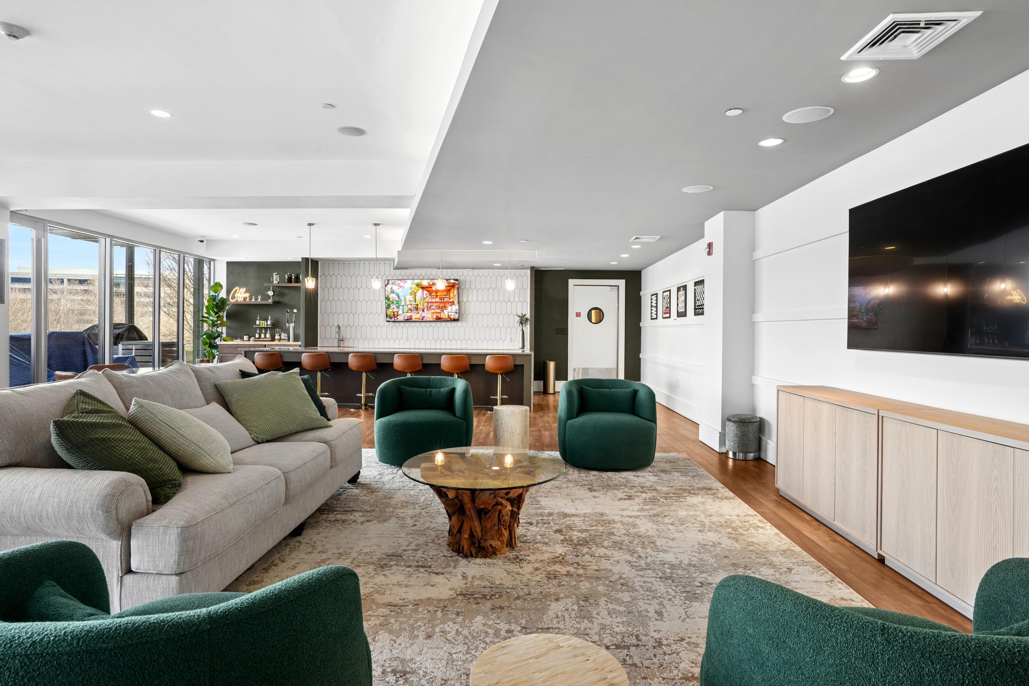 Modern lounge with green chairs, sofa, and a bar area.