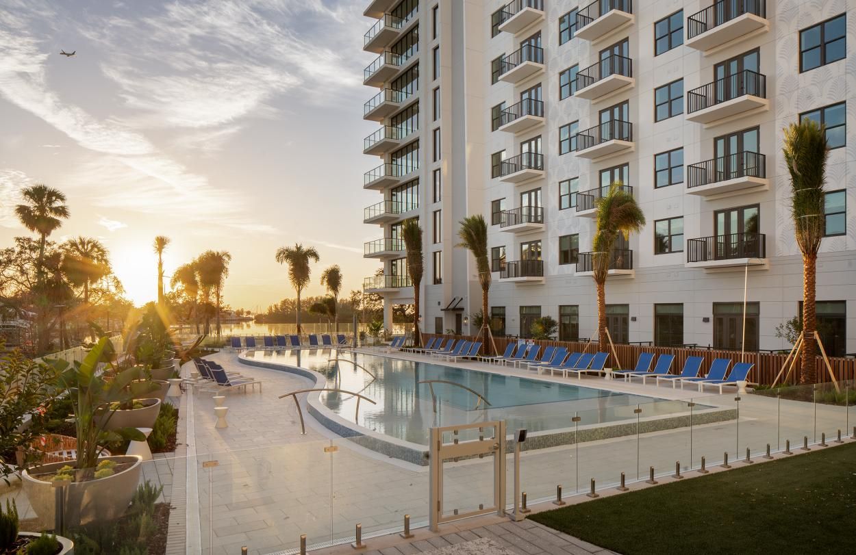 Modern building by a sunset pool with palm trees.