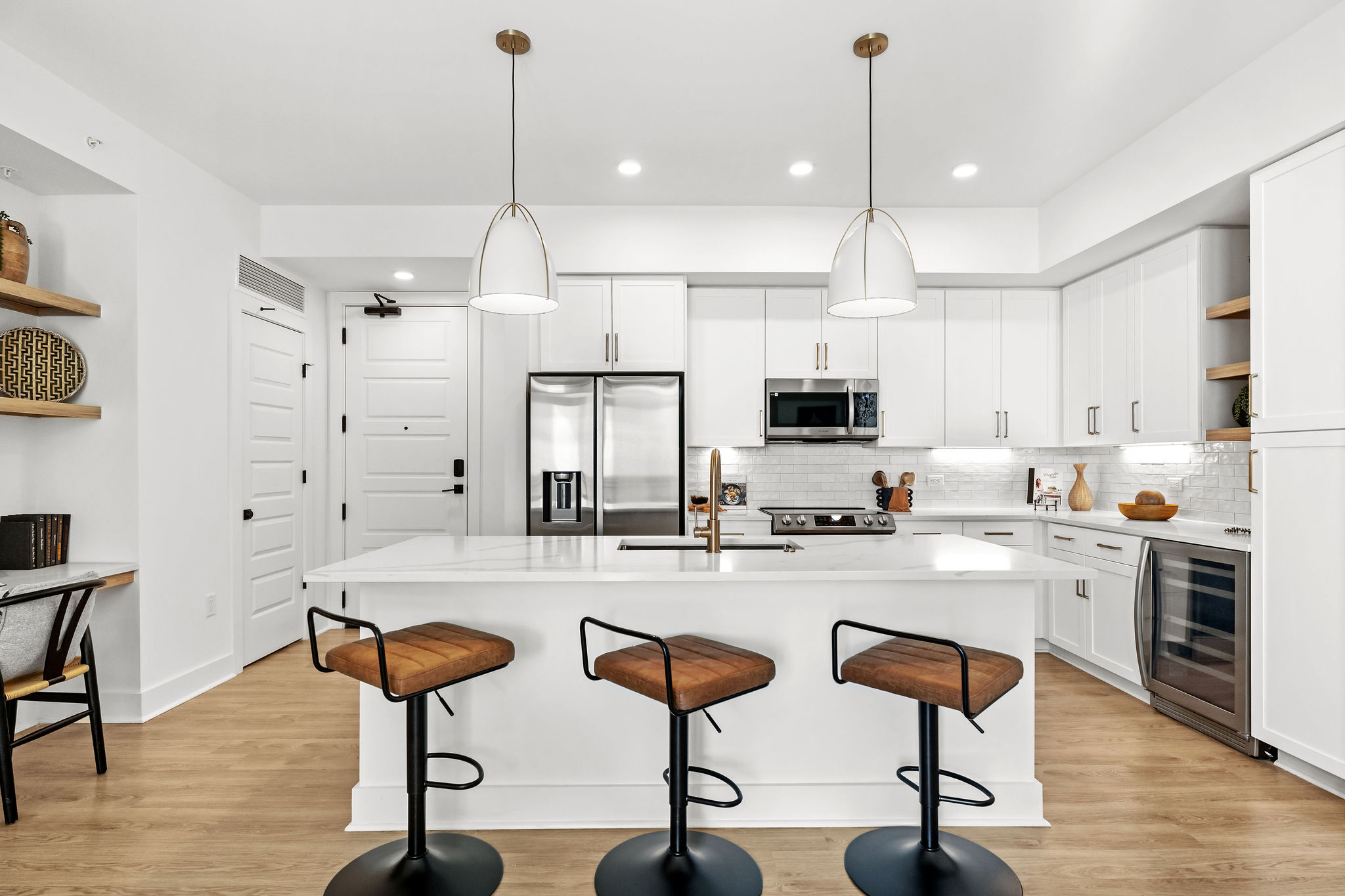 Modern kitchen with white cabinets, stainless steel appliances, and barstool seating.