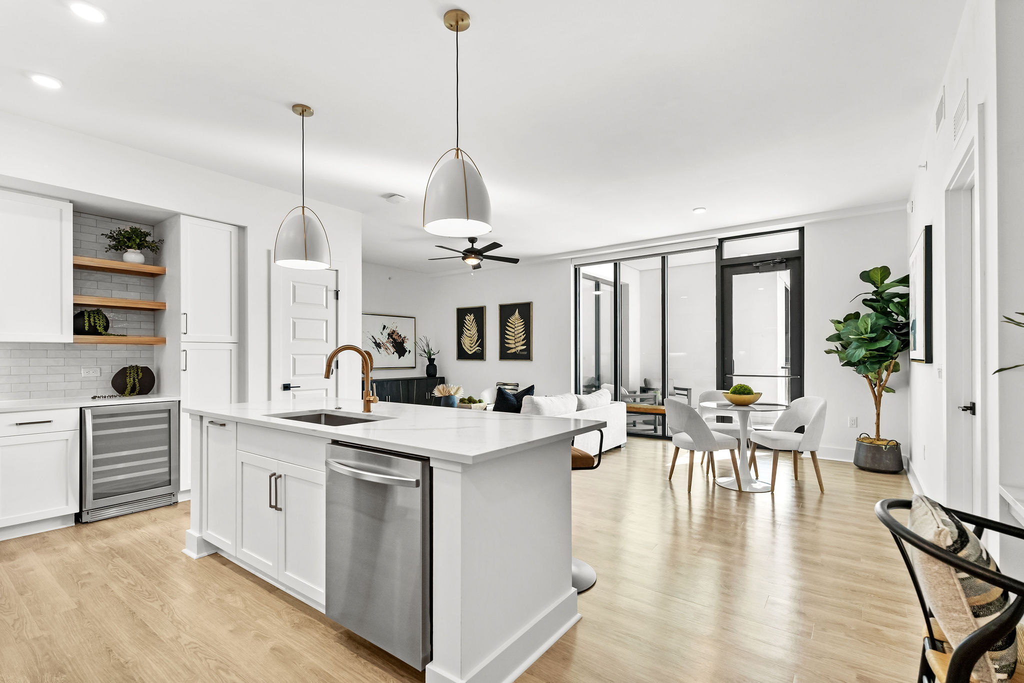 Modern open kitchen and dining area with white cabinetry and large windows.