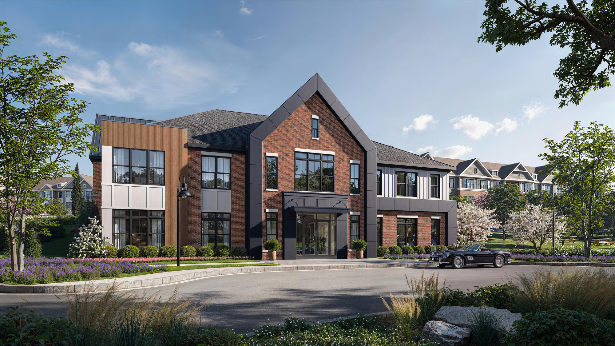 n exterior view of a modern apartment clubhouse featuring large glass windows, a landscaped front entrance, and a paved walkway.