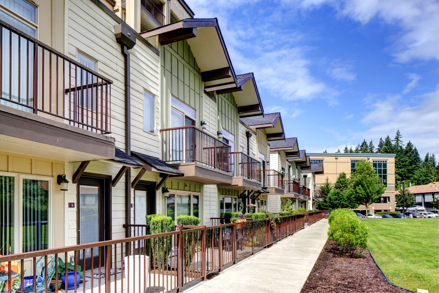 Row of modern townhouses with balconies and green landscaping.
