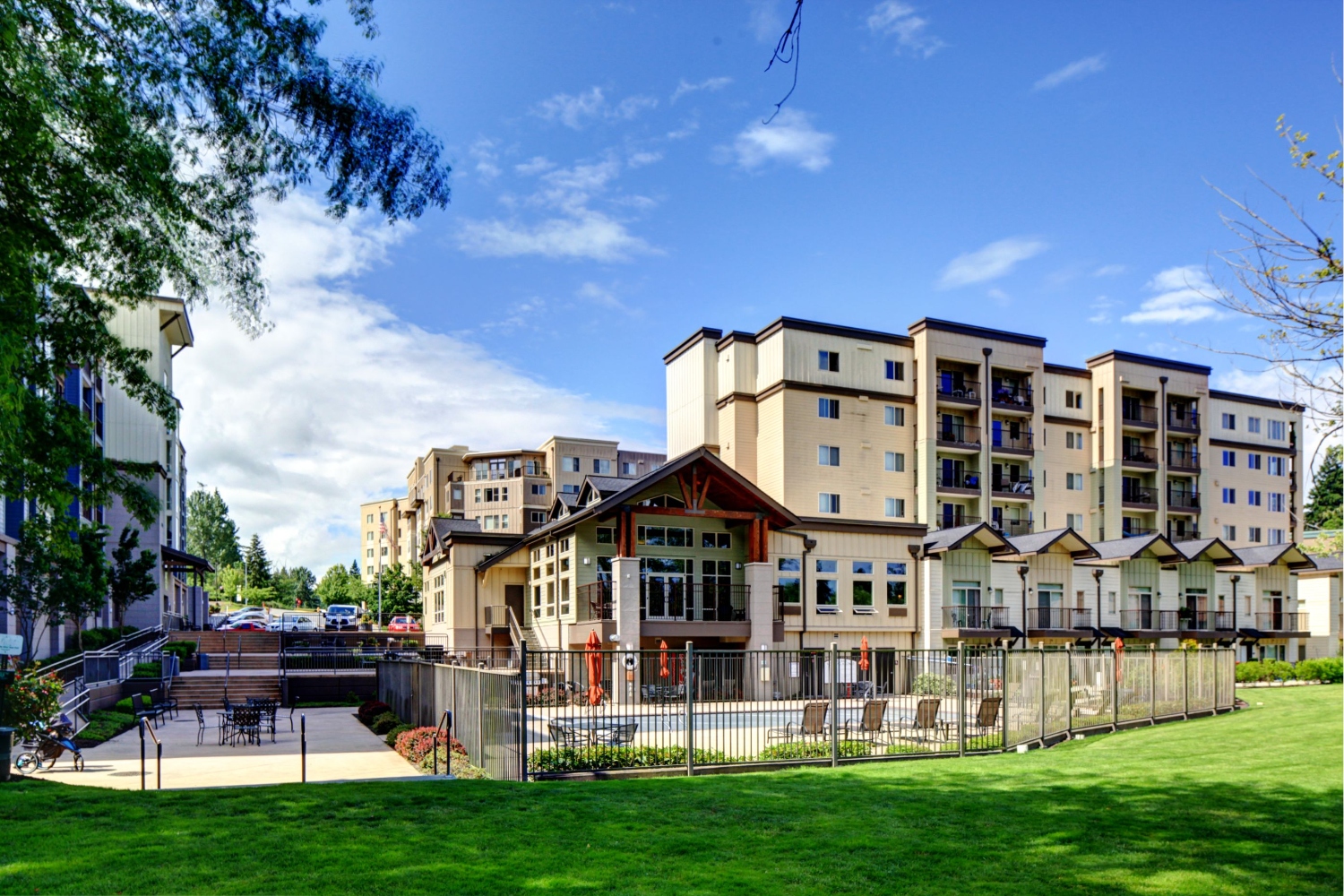 Modern multi-story building with blue sky and greenery nearby.