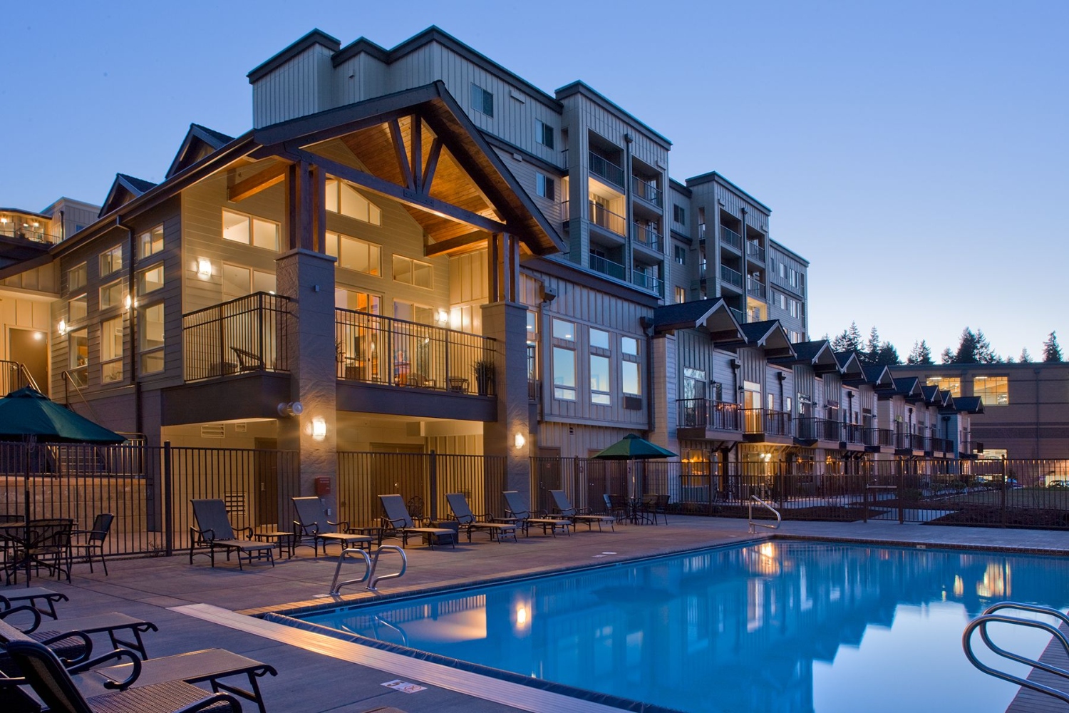 Modern apartment complex with a pool at twilight.