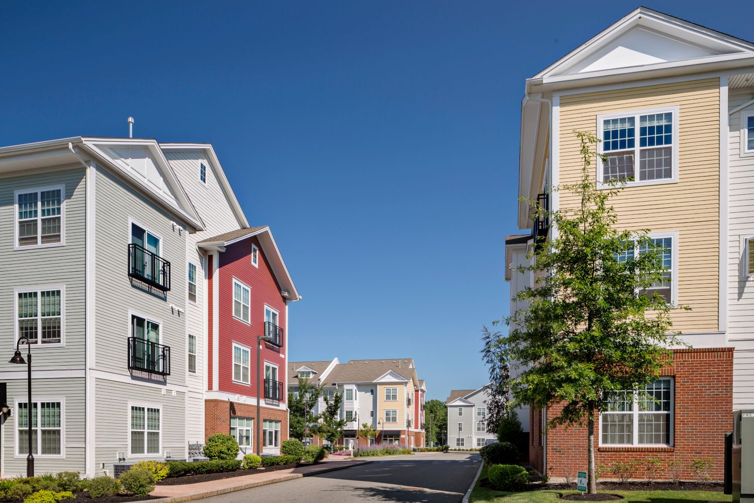 Two residential buildings in a sunny neighborhood with clear blue skies.