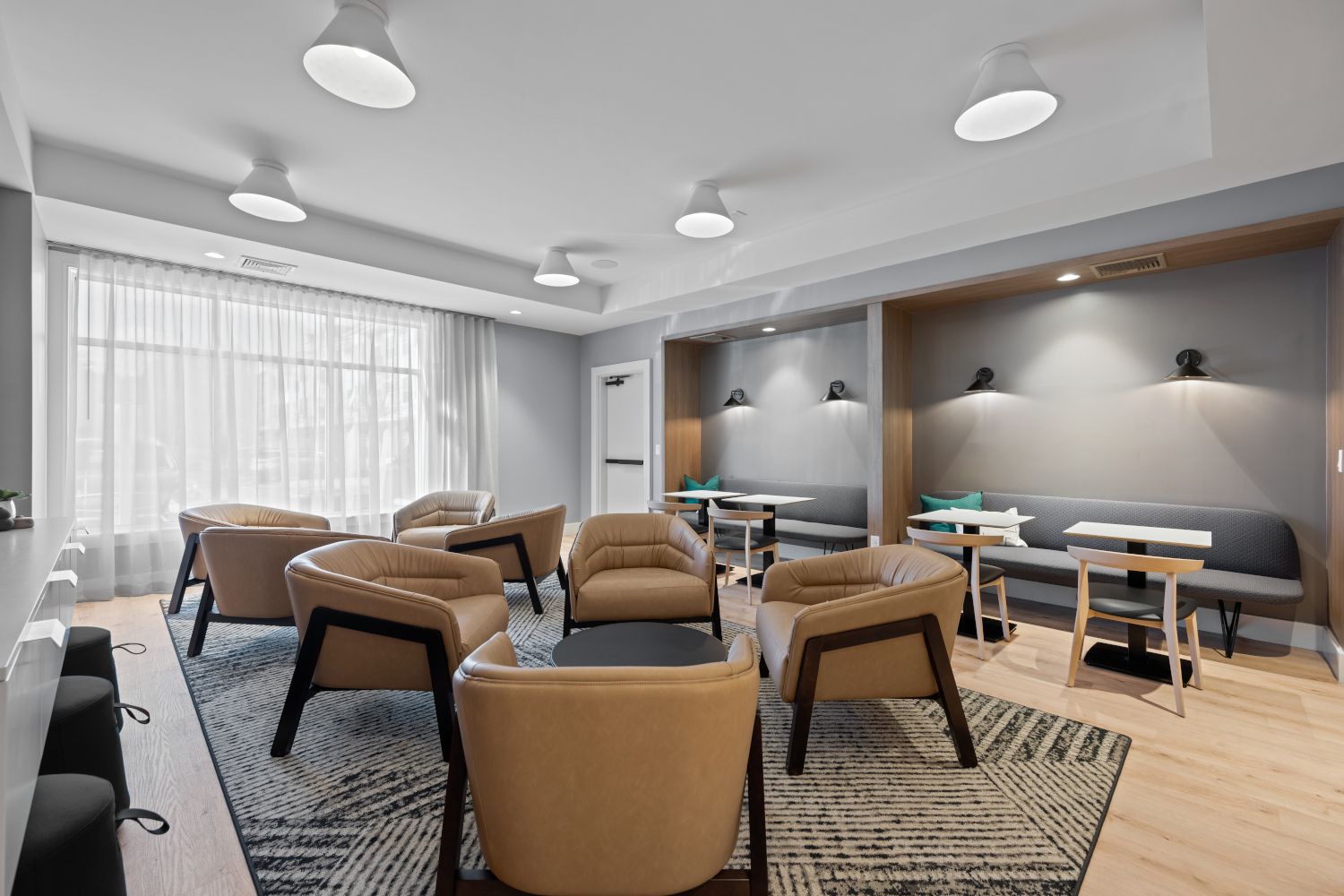 Modern lounge with brown chairs, tables, and bright lighting.