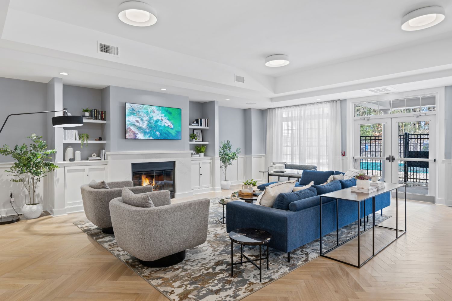 Modern living room with a fireplace, stylish furniture, and large windows.