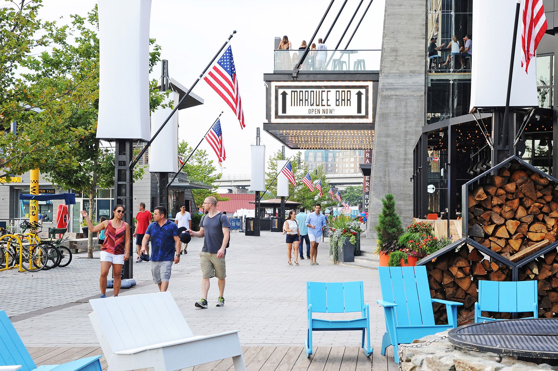 Outdoor scene with people walking near shops and American flags in a vibrant area.
