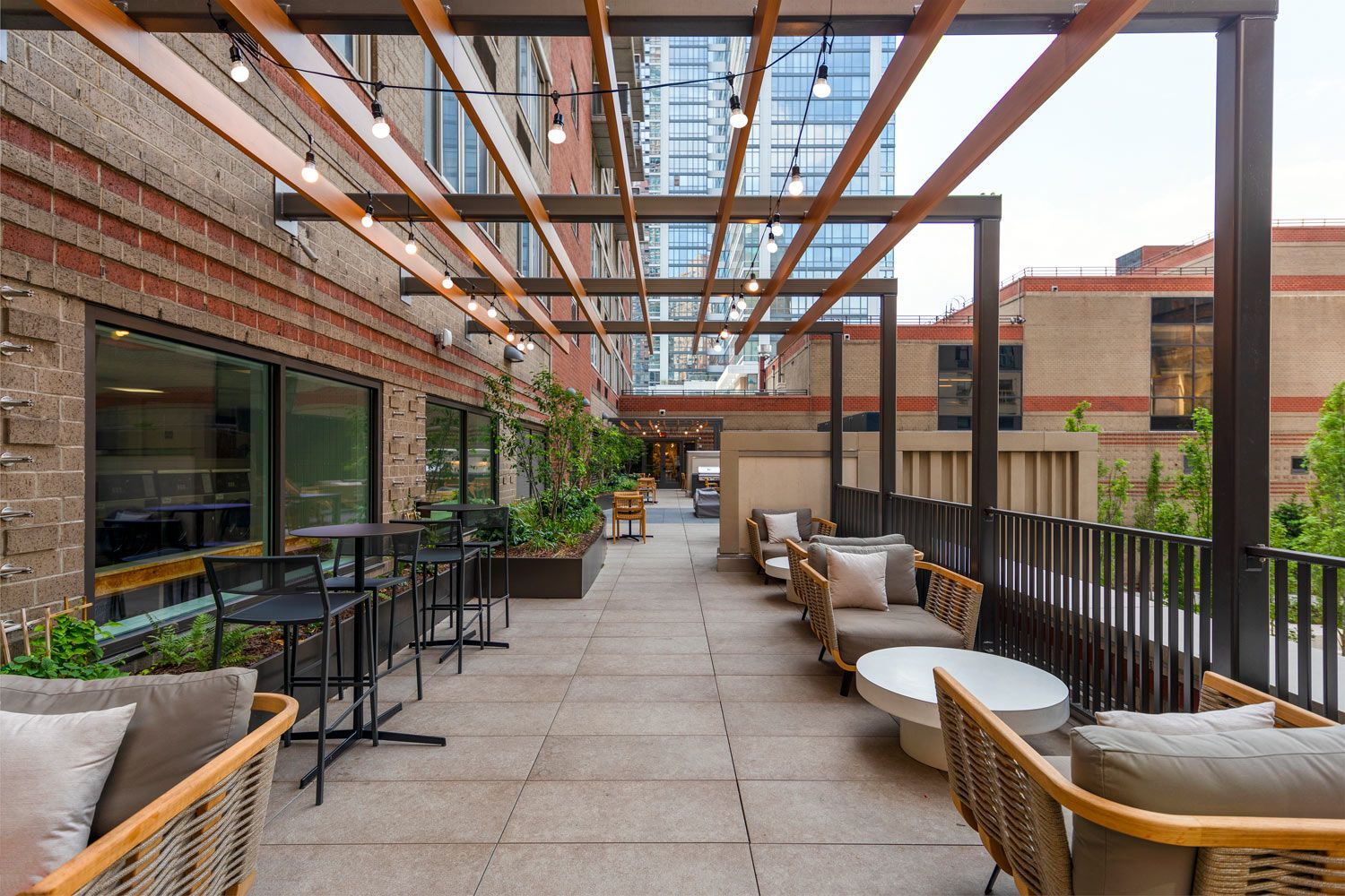 A modern outdoor patio with seating, plants, and string lights.