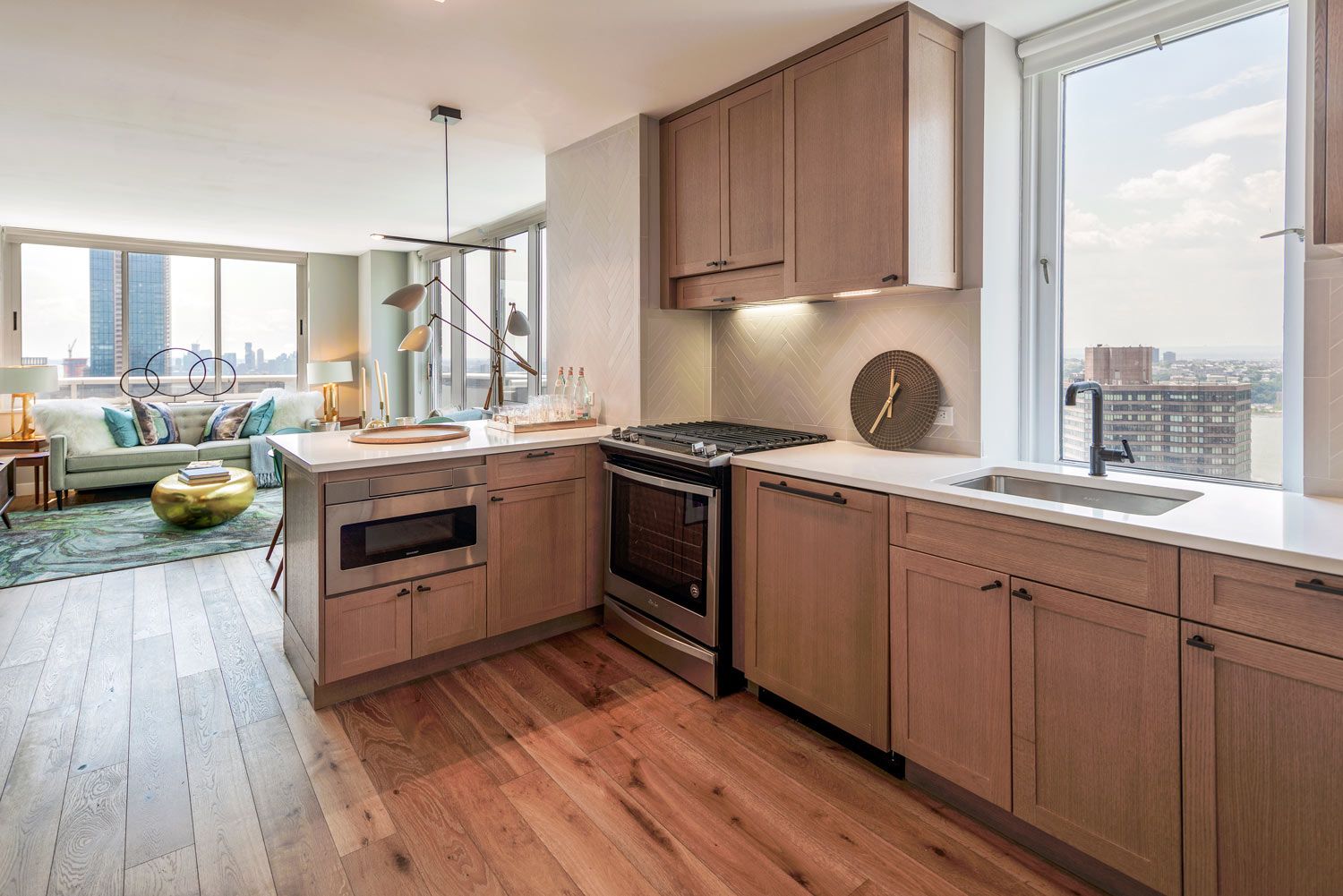 Modern kitchen with wooden cabinets and stainless steel appliances, overlooking a city view.