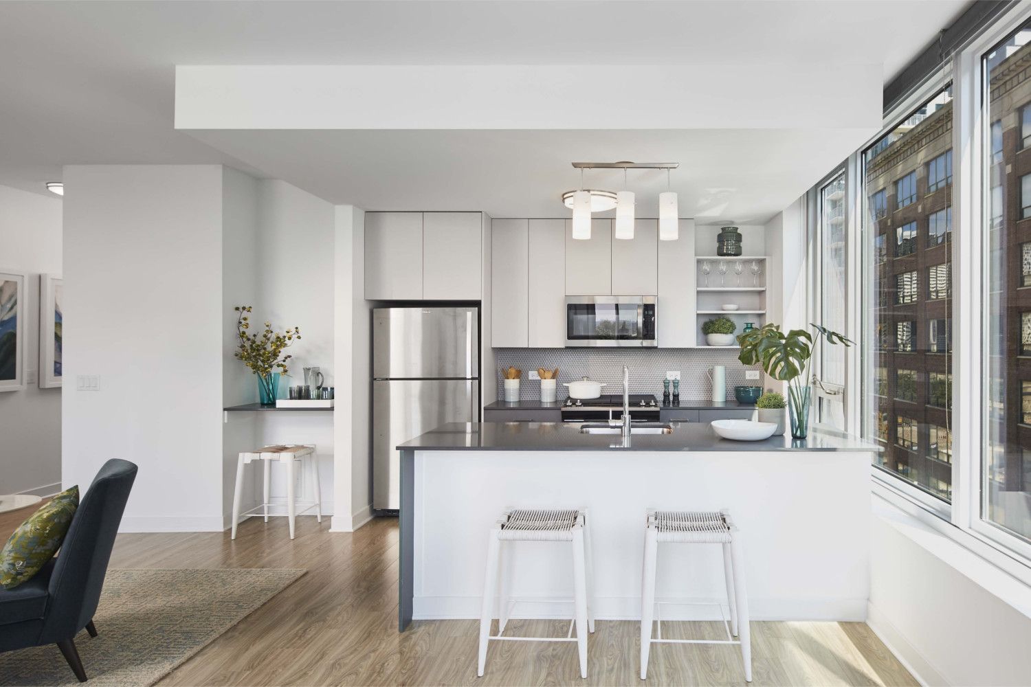 Modern kitchen with light cabinets, stainless appliances, and large windows.