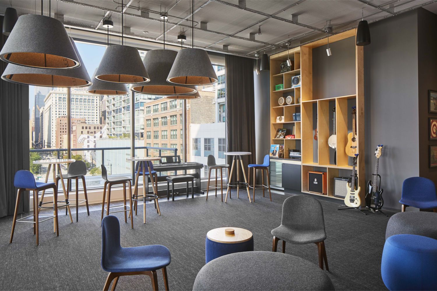Modern lounge with chairs, shelves, and large windows overlooking a cityscape.