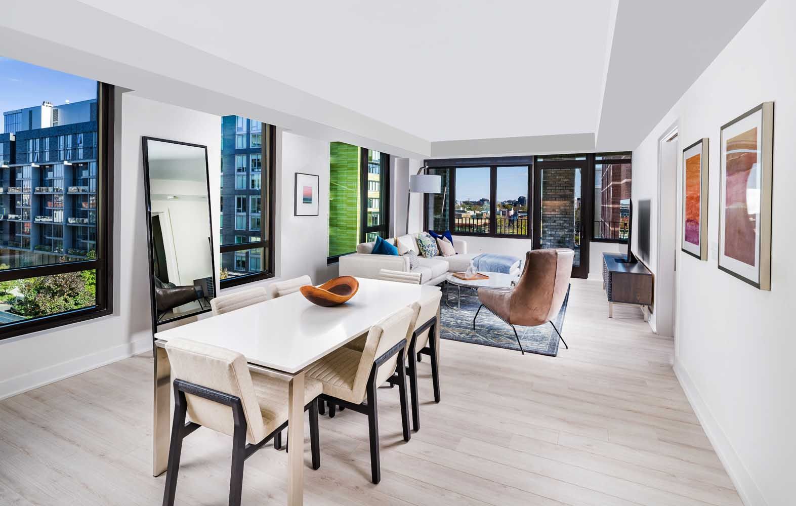 Expansive living room areas with wide-plank, wood-style flooring and large windows with shade window treatments