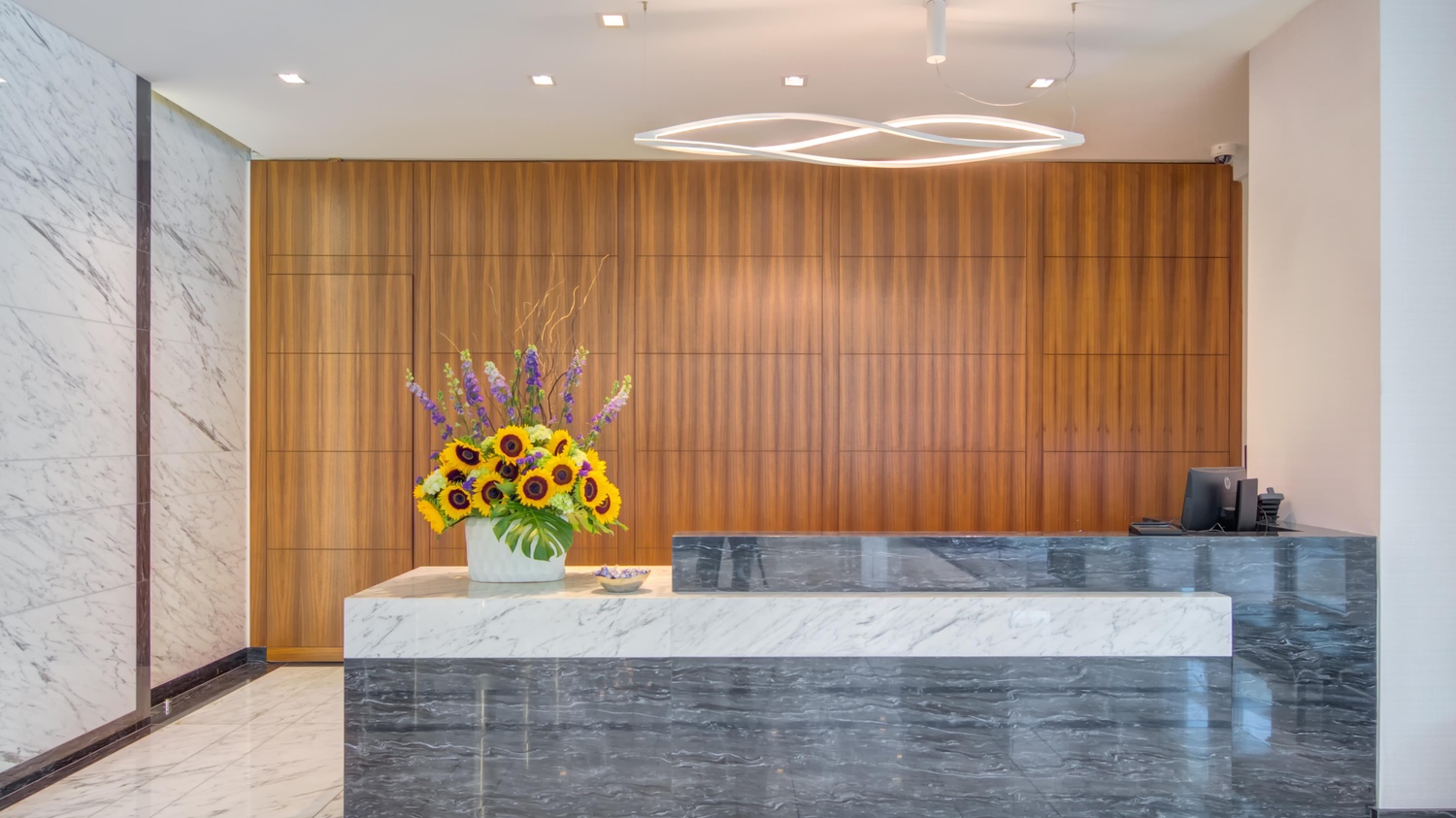 Concierge desk with florals in modern lobby.