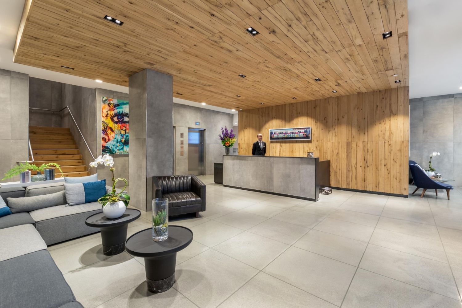 Modern lobby with wooden accents, a reception desk, seating area, and artistic decor.