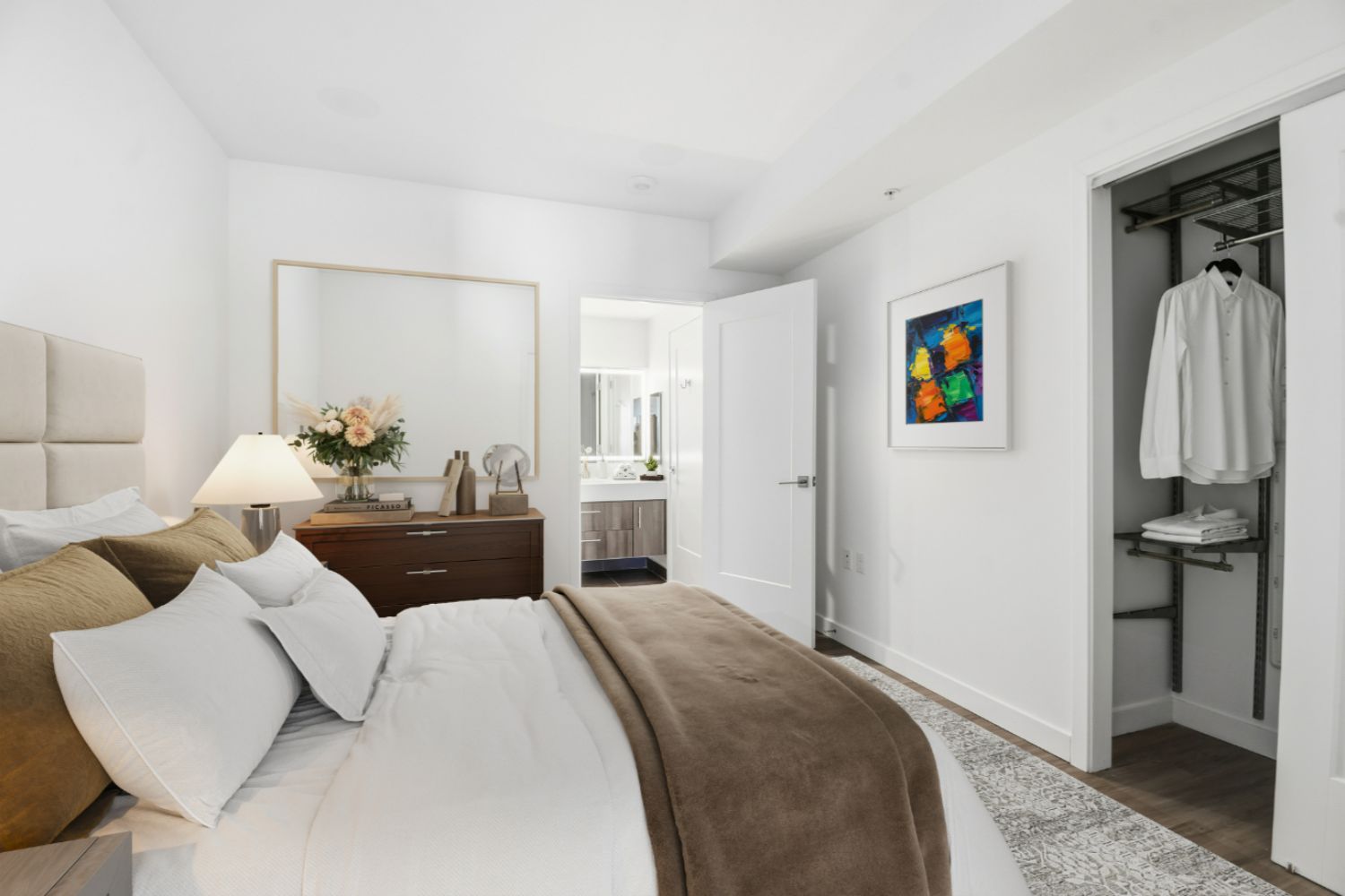 Bedroom with brown blanket and bathroom in distance