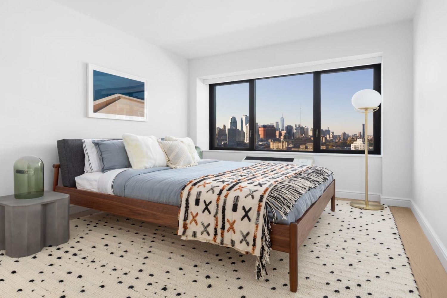 Bright bedroom with a city view, modern furnishings, and neutral tones.