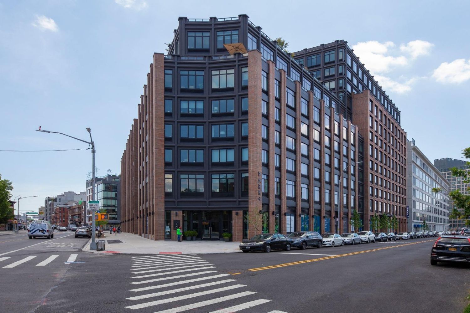 Modern brick building at a city intersection under a clear blue sky.