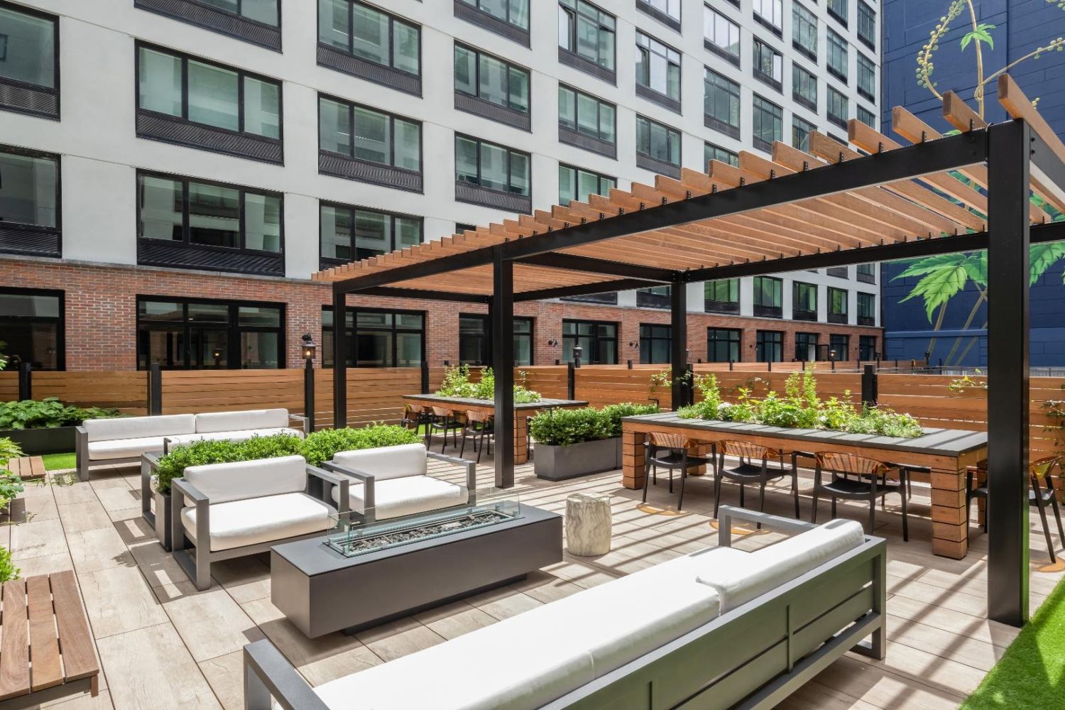 Modern outdoor lounge area with seating and greenery in an urban setting.