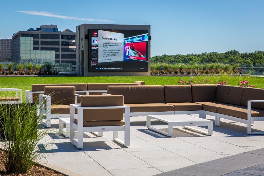 Outdoor seating area with brown cushions and a large screen in the background.