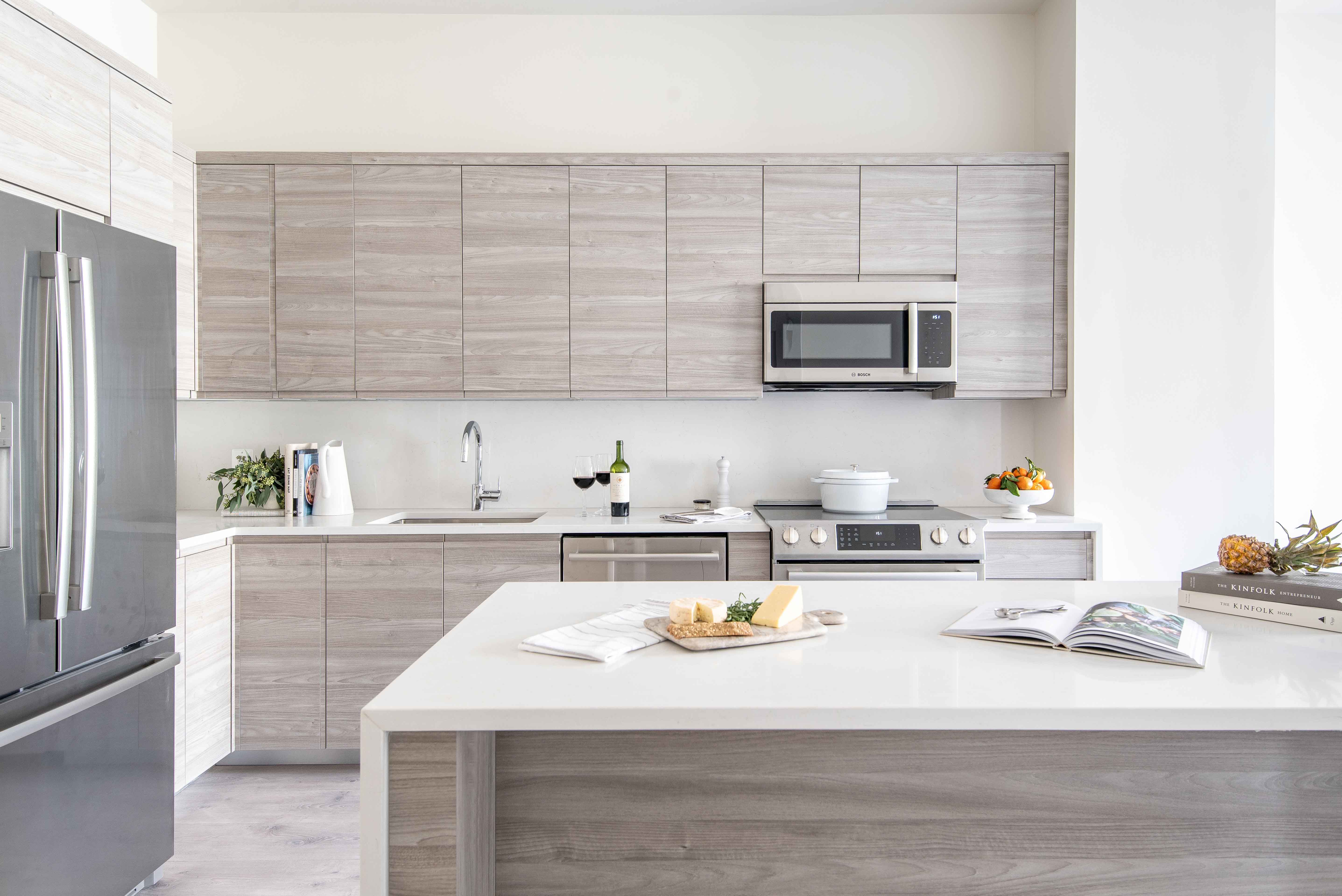 Modern kitchen with gray cabinetry, stainless steel appliances, and a central island.