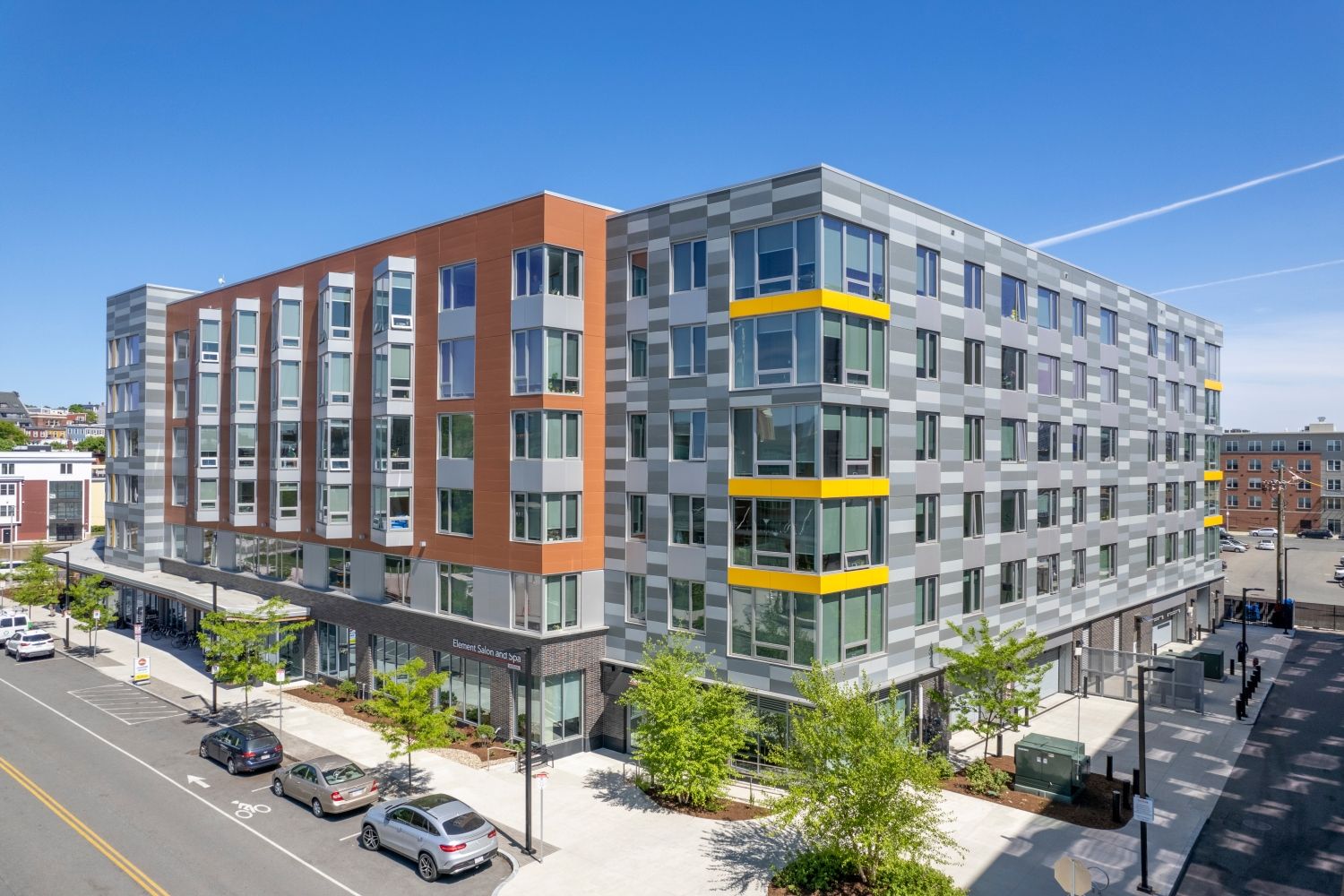 Modern multi-story apartment building with a mix of brick and glass facades.