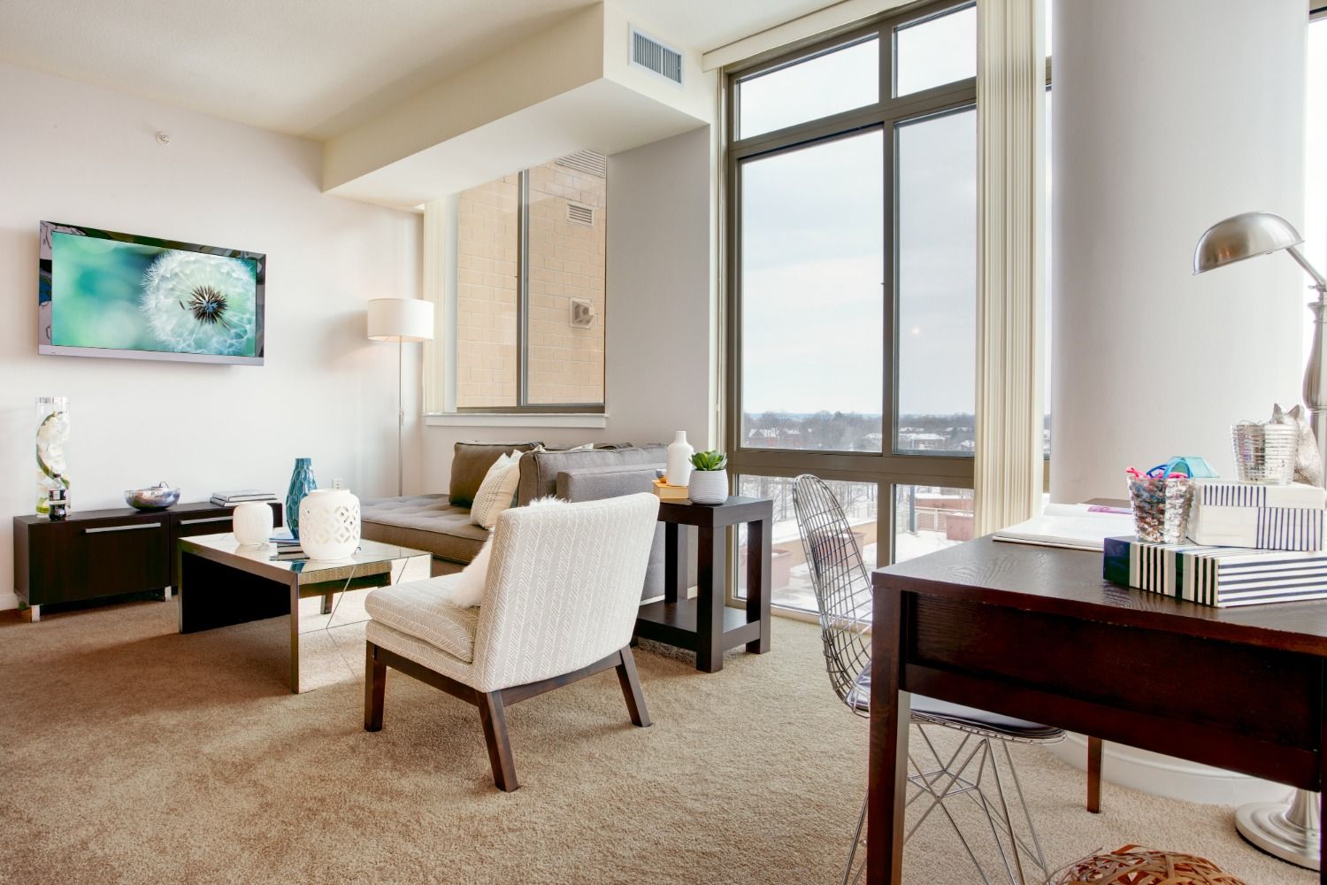 Modern living room with a large window, stylish furniture, and a desk.