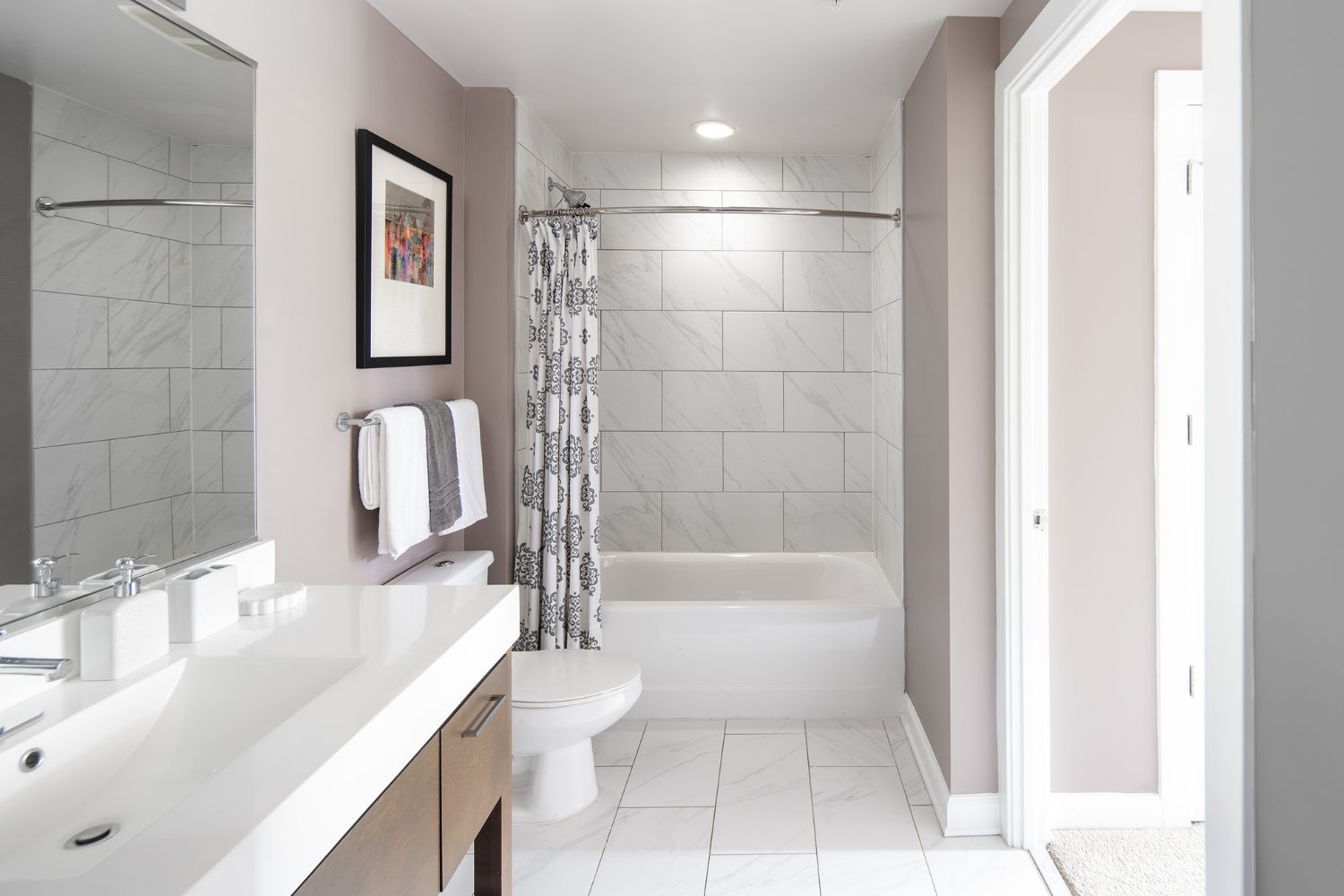 Sleek bathrooms featuring linen tiling and Carrara marble vanities
