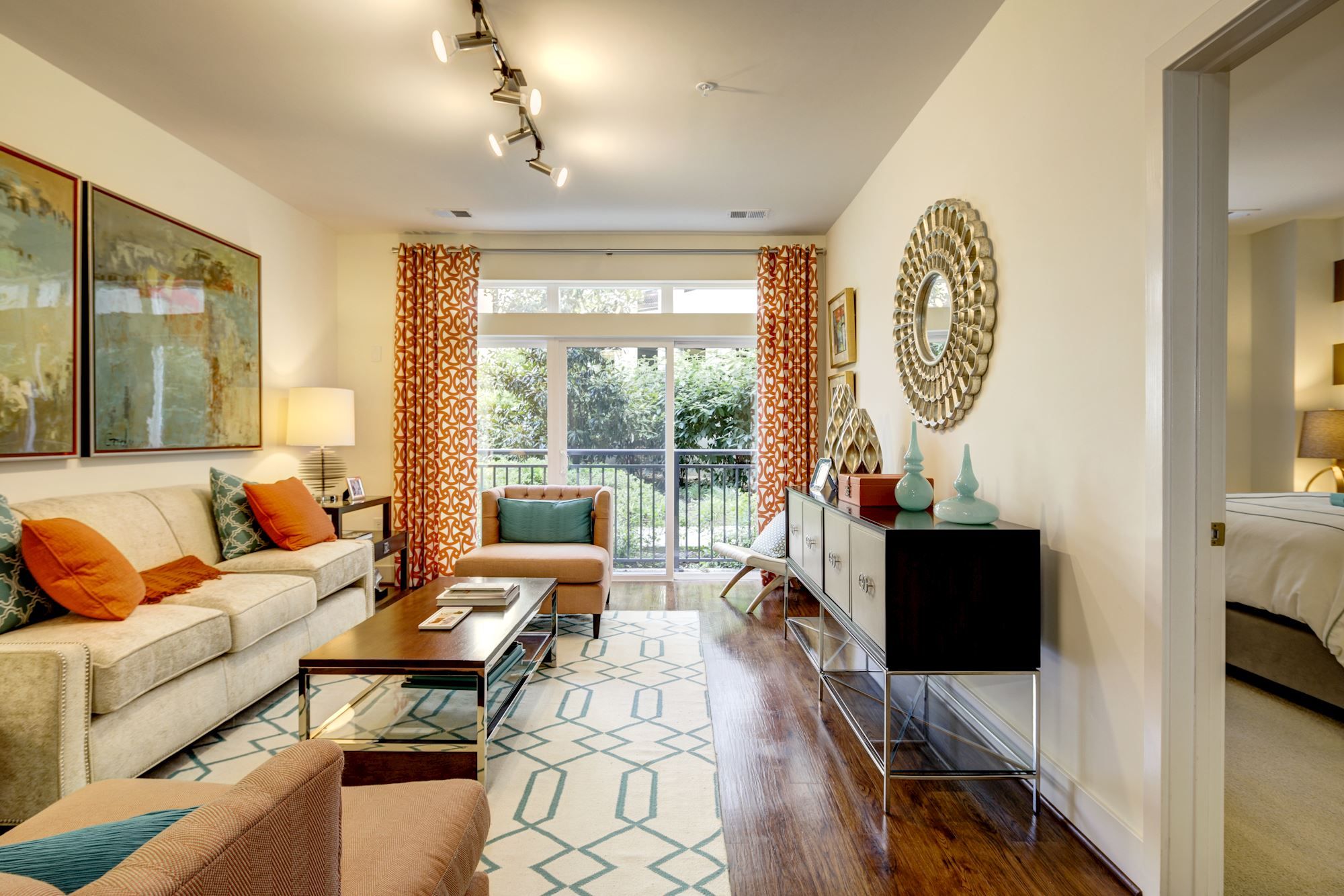 Bright modern living room with orange accents and large windows.