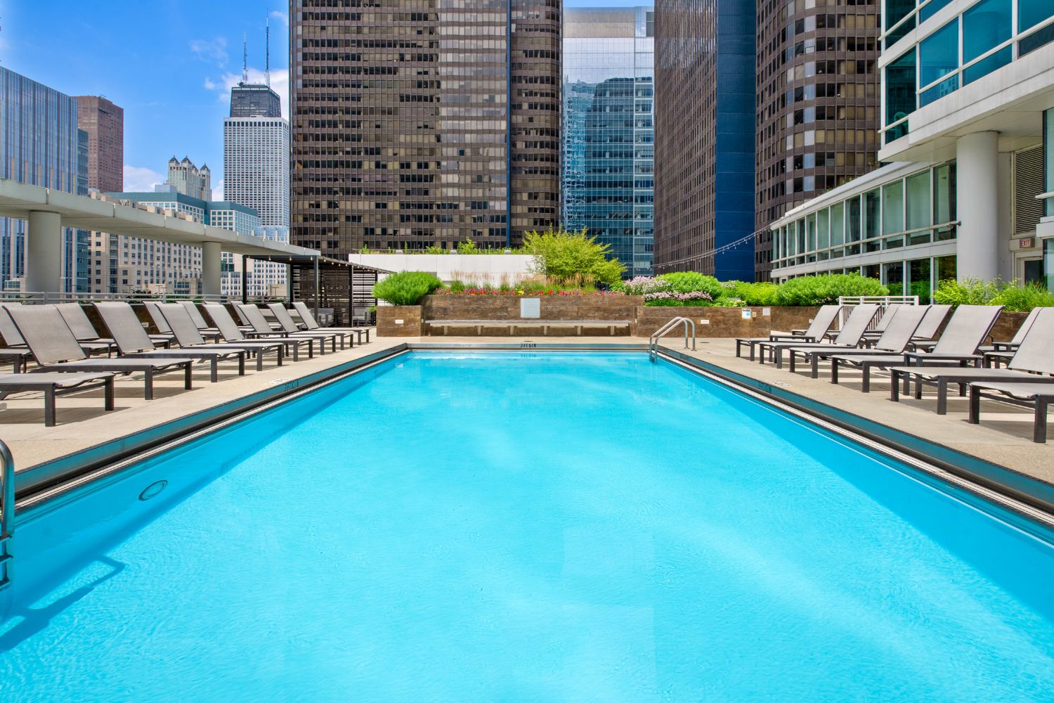 Wide angle of Atwater's outdoor sundeck featuring a resort-style pool and lounge seating with the cityscape in the background.