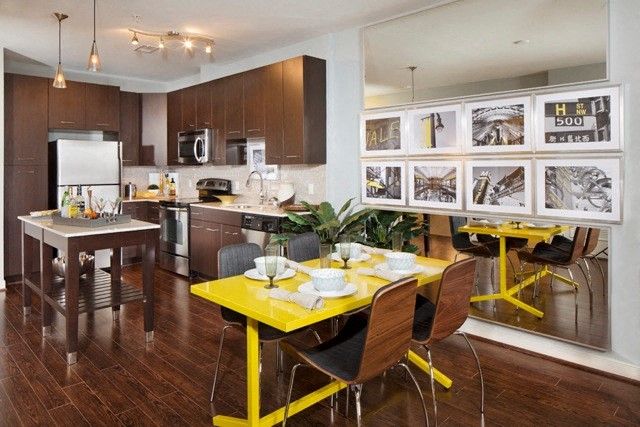Modern kitchen with dark cabinets, stainless appliances, and a bright yellow dining table.