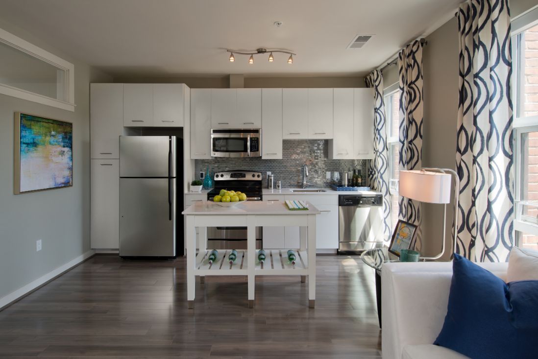Modern kitchen with white cabinets, stainless appliances, and a small island with fruit.
