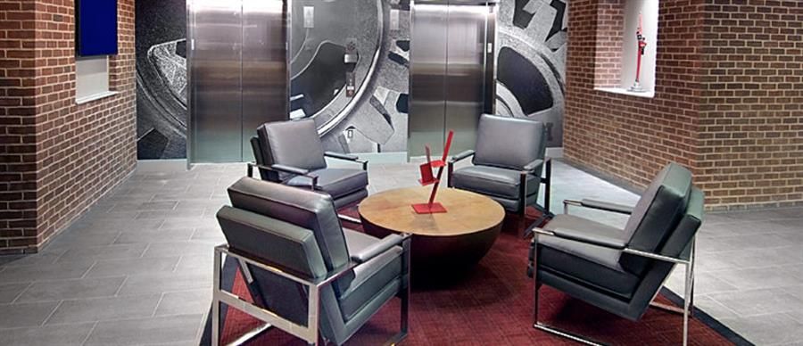 Modern seating area with four chairs and a round table against a brick wall backdrop.