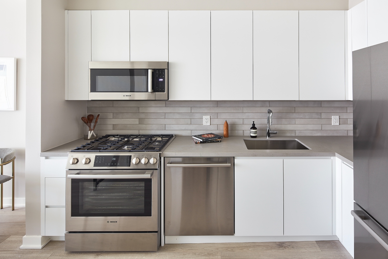 Modern kitchen with white cabinets, stainless steel appliances, and a gray backsplash.