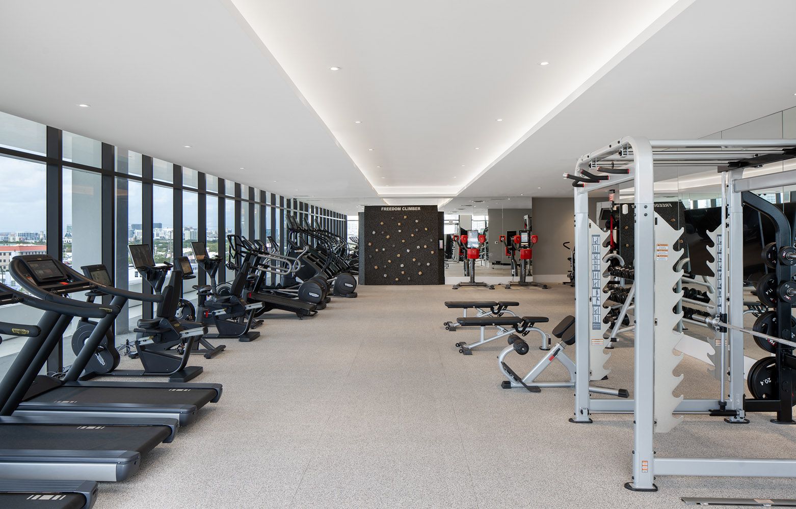 Modern gym interior with exercise equipment and large windows.