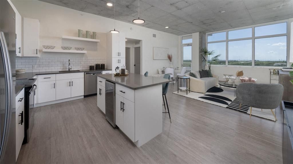 Modern kitchen and living area with large windows and minimalist decor.