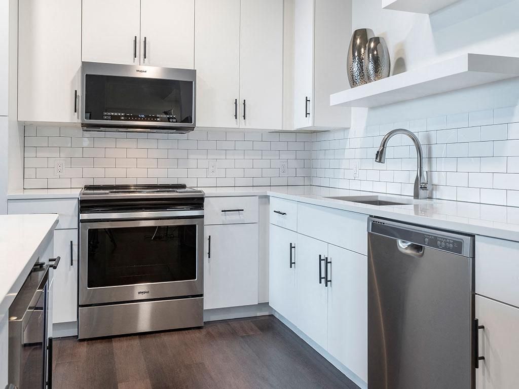 Modern kitchen with white cabinets, stainless steel appliances, and a sleek countertop.
