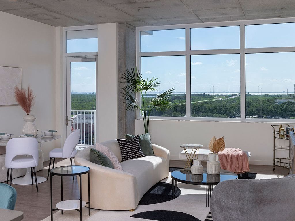Modern living room with large windows, stylish furniture, and views of greenery outside.
