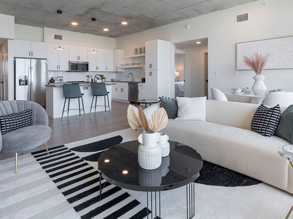 Modern living room with a sofa, round coffee table, and open kitchen in a bright space.